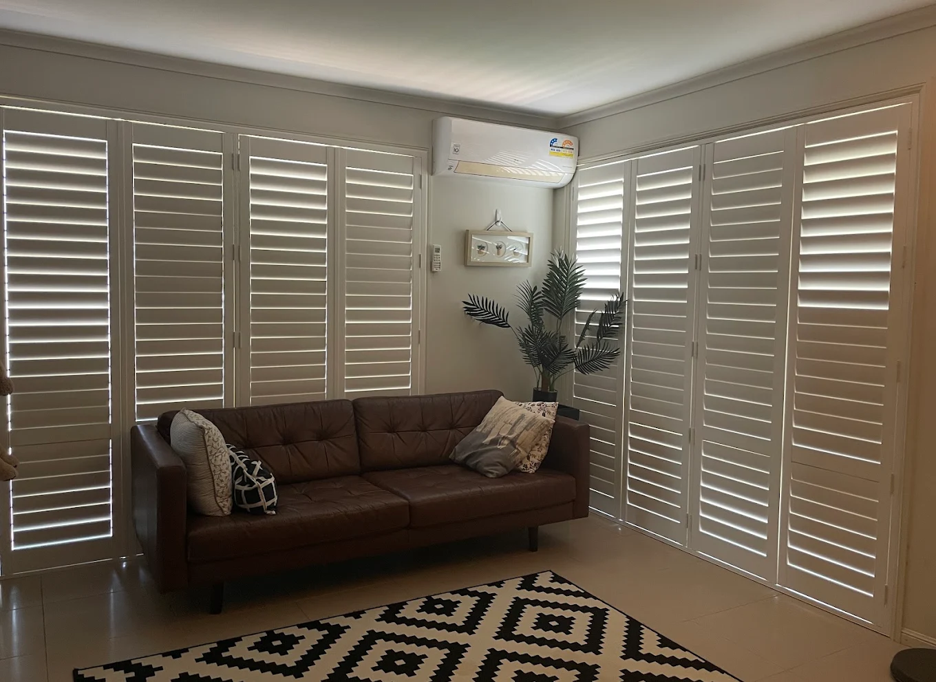 Living room with white plantation shutters and brown leather sofa