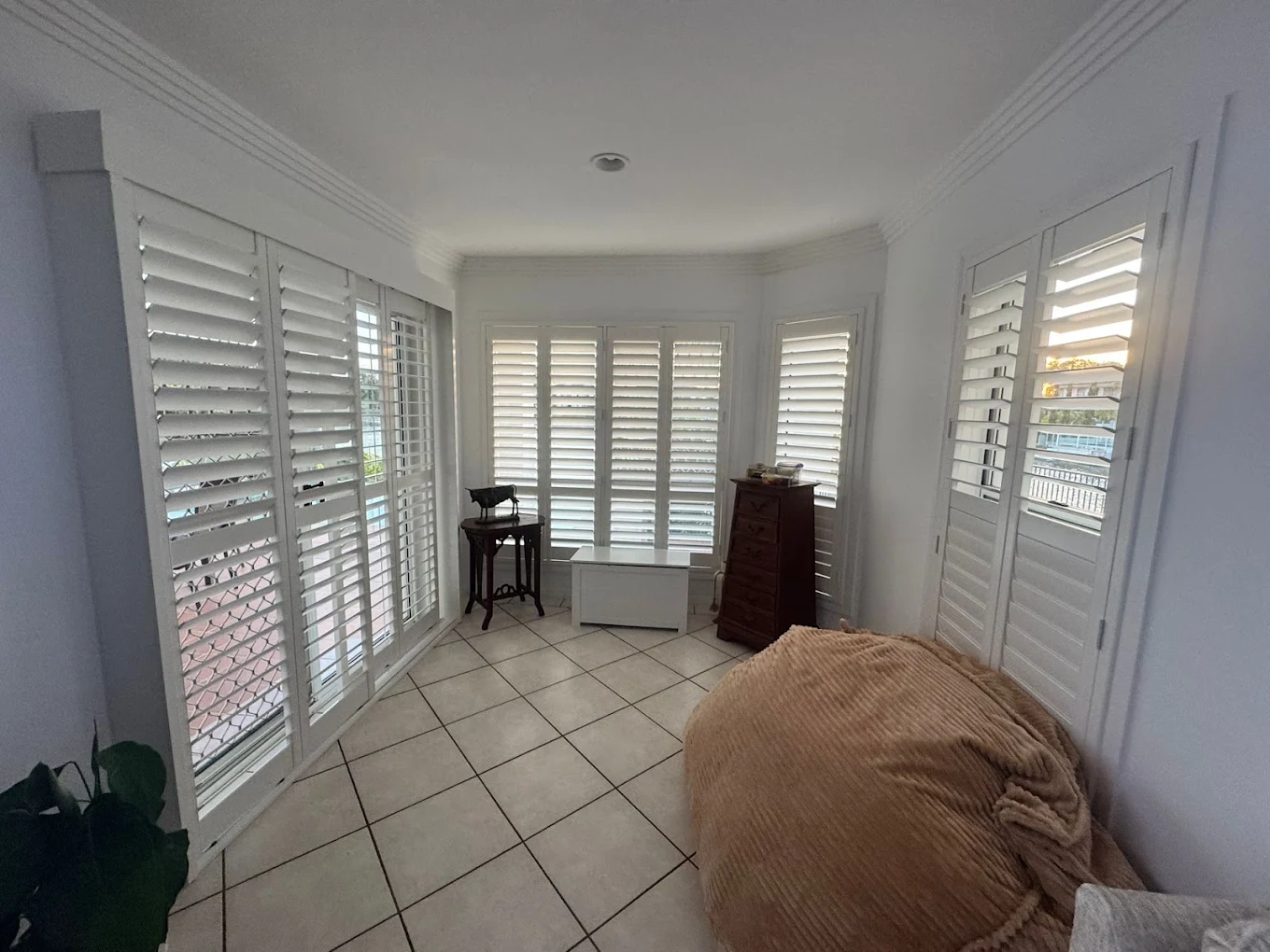 White plantation shutters fitted around a bright corner room