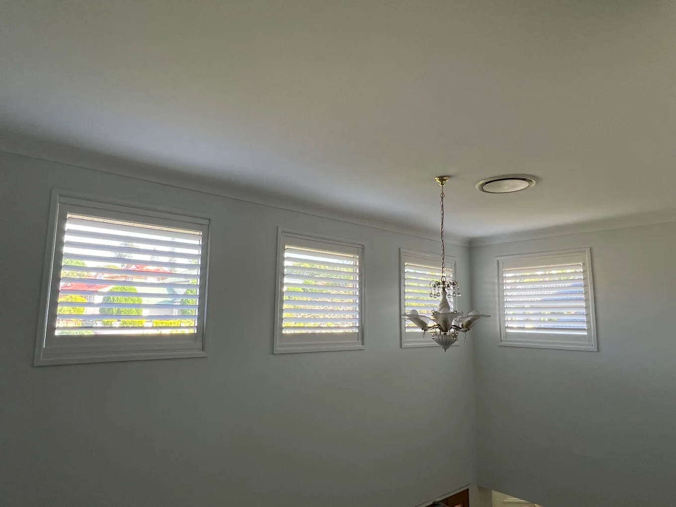 Four windows with white plantation shutters in a bright room